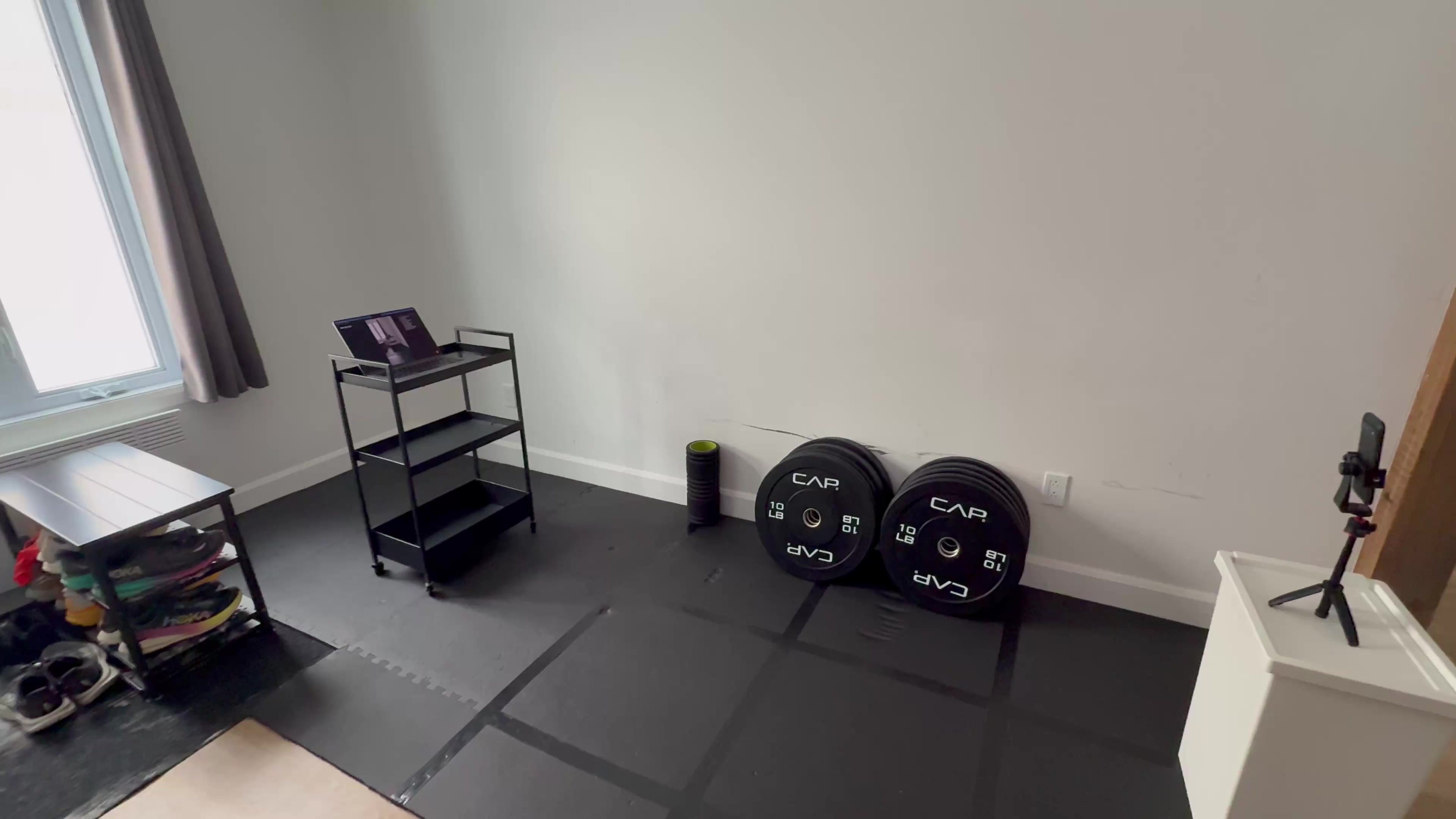 Home exercise setup with tripod, open floor space, and side filming angle